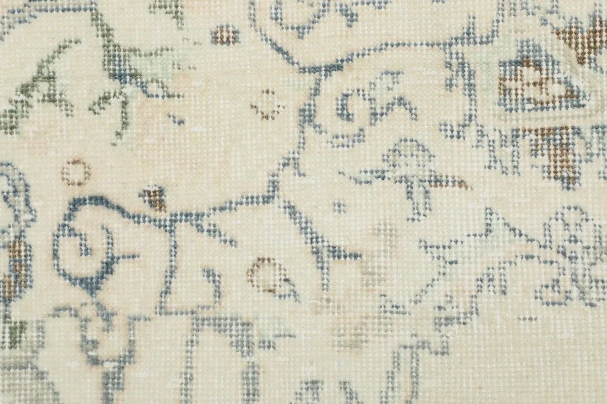 Detailed view of the intricate gray scrollwork motifs within the border of the rug