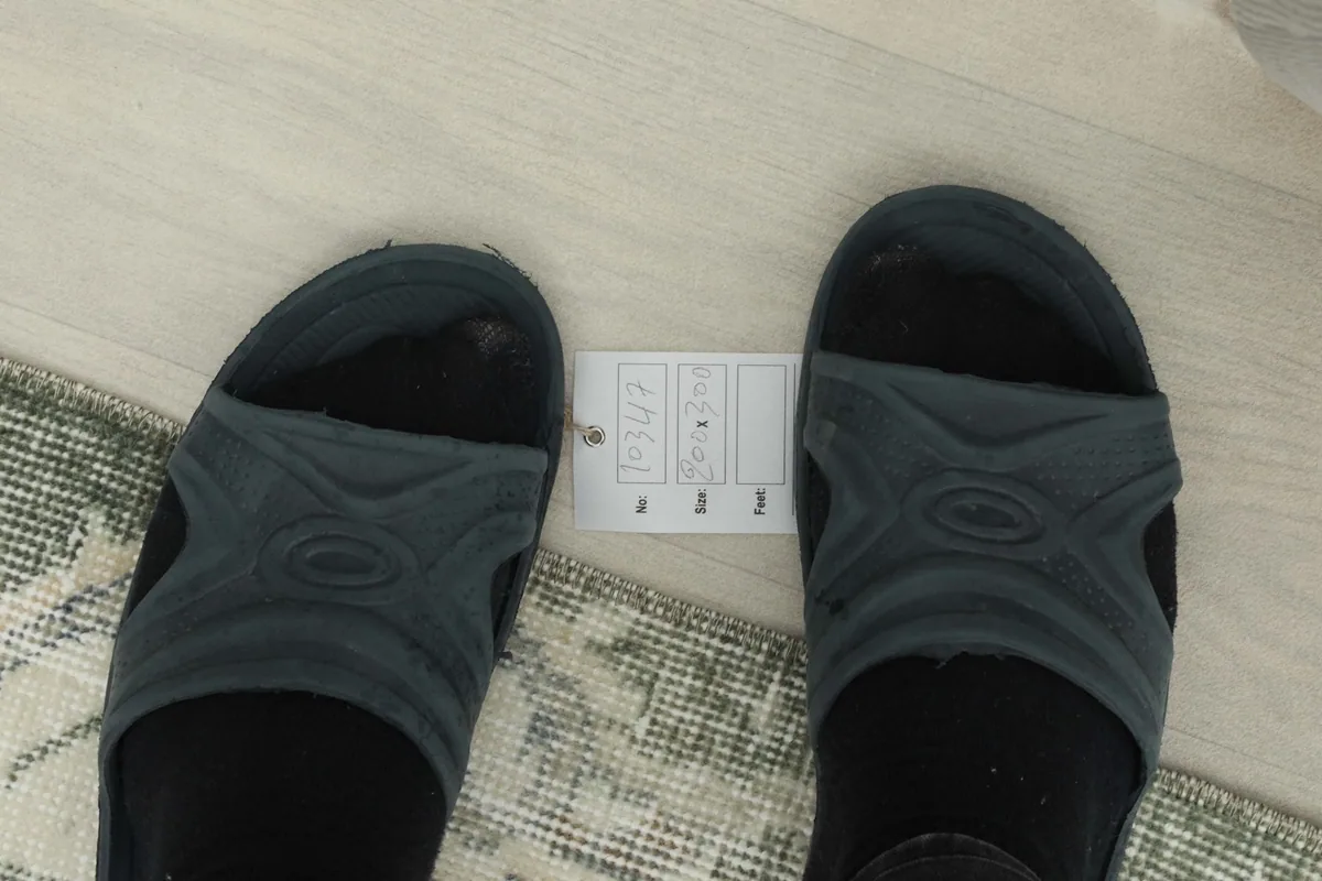 View of a foot next to the rug, indicating the low pile height and scale of the pattern
