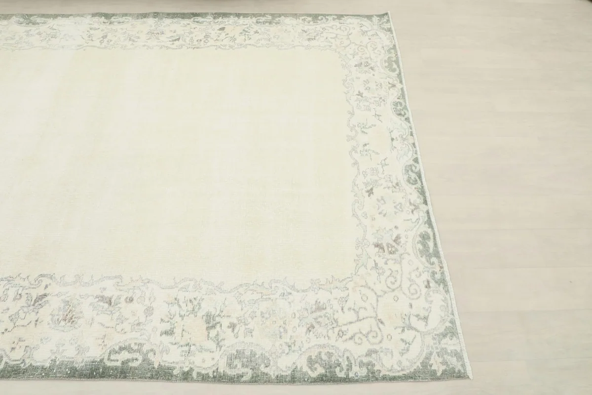 Overhead view showing the corner of the ivory and gray vintage rug on a light floor