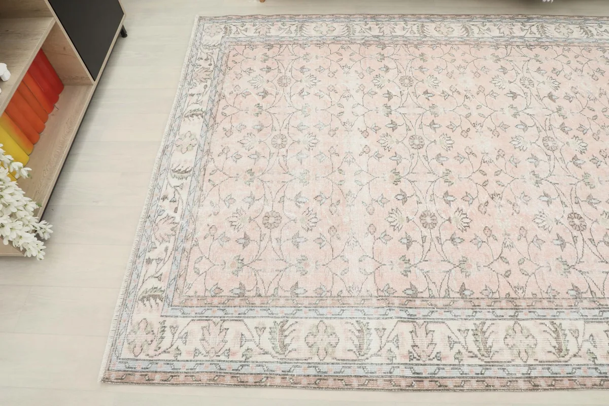 Angled view of the rug's soft rose field and gray floral details