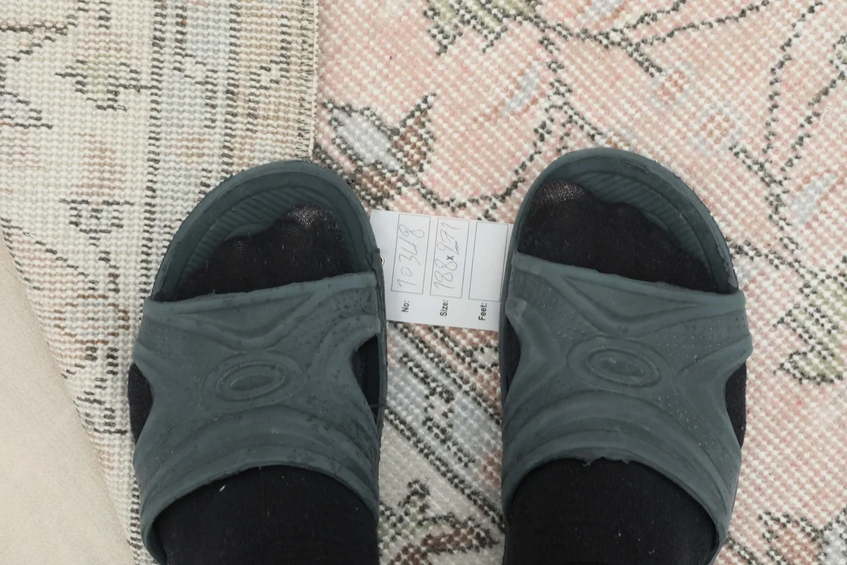 View from above showing feet for scale next to the rug's soft rose pattern