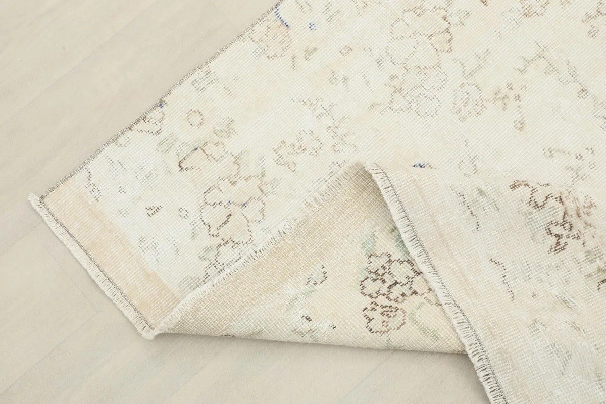 Corner of the rug folded back, revealing the cotton foundation and hand-knotted construction