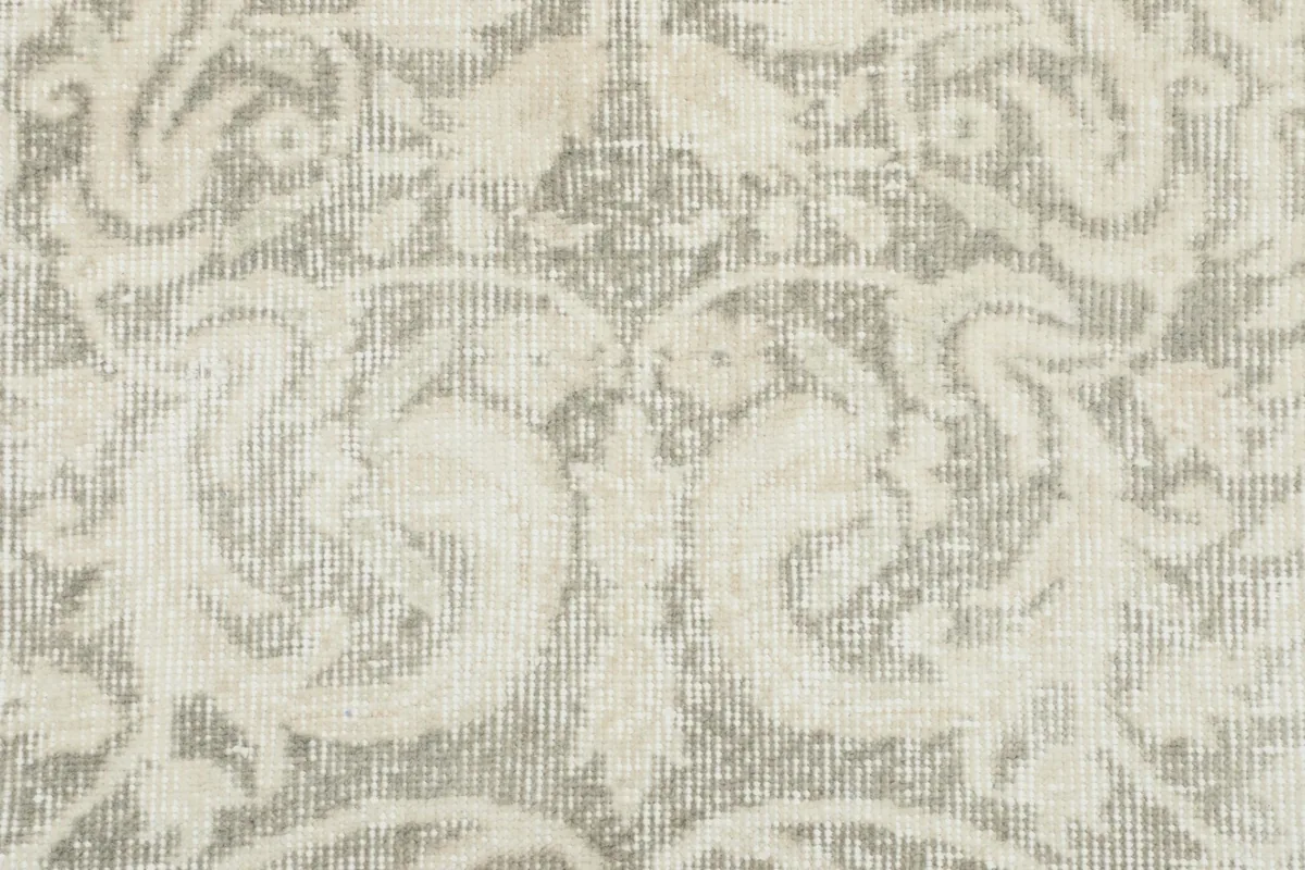 Detailed view of the rug's surface, showing the faded gray background and raised ivory motifs