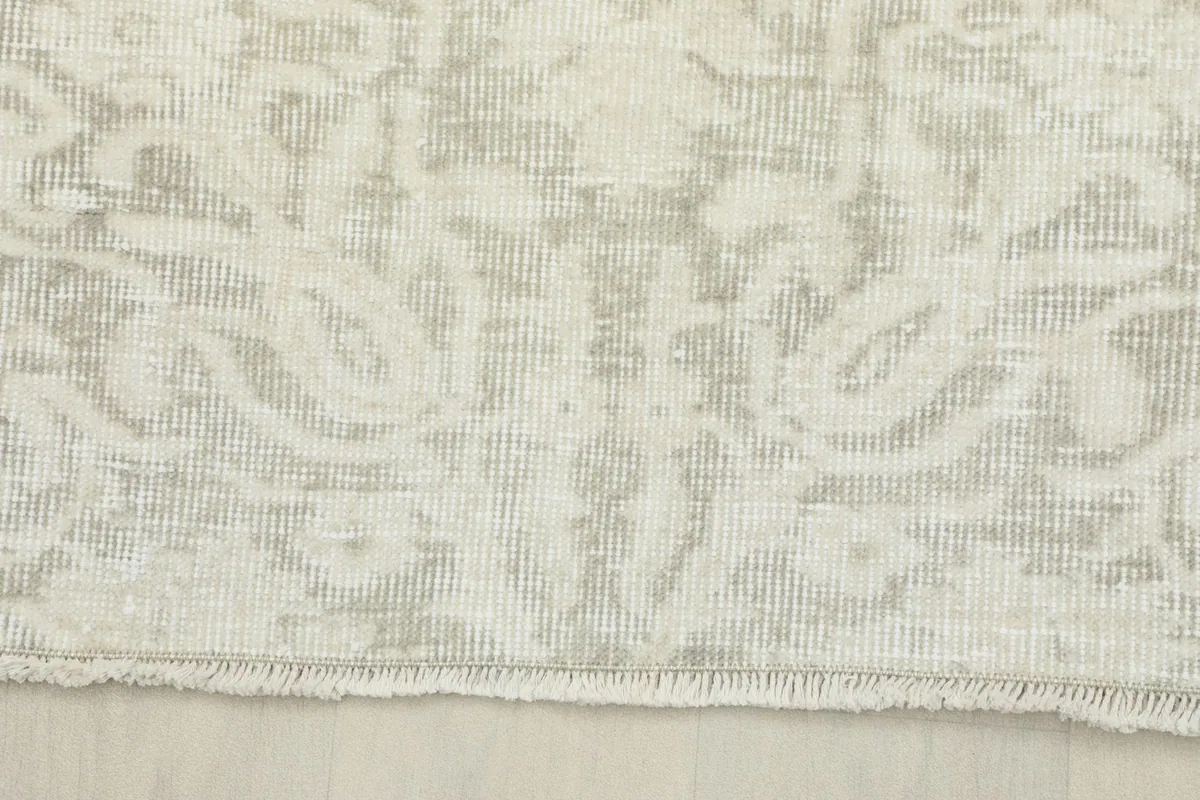 Edge of the vintage wool rug, showing the short, natural fringe and border detail