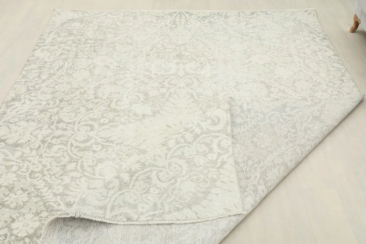 Overhead view with a corner folded back, showing the reverse side of the hand-knotted rug