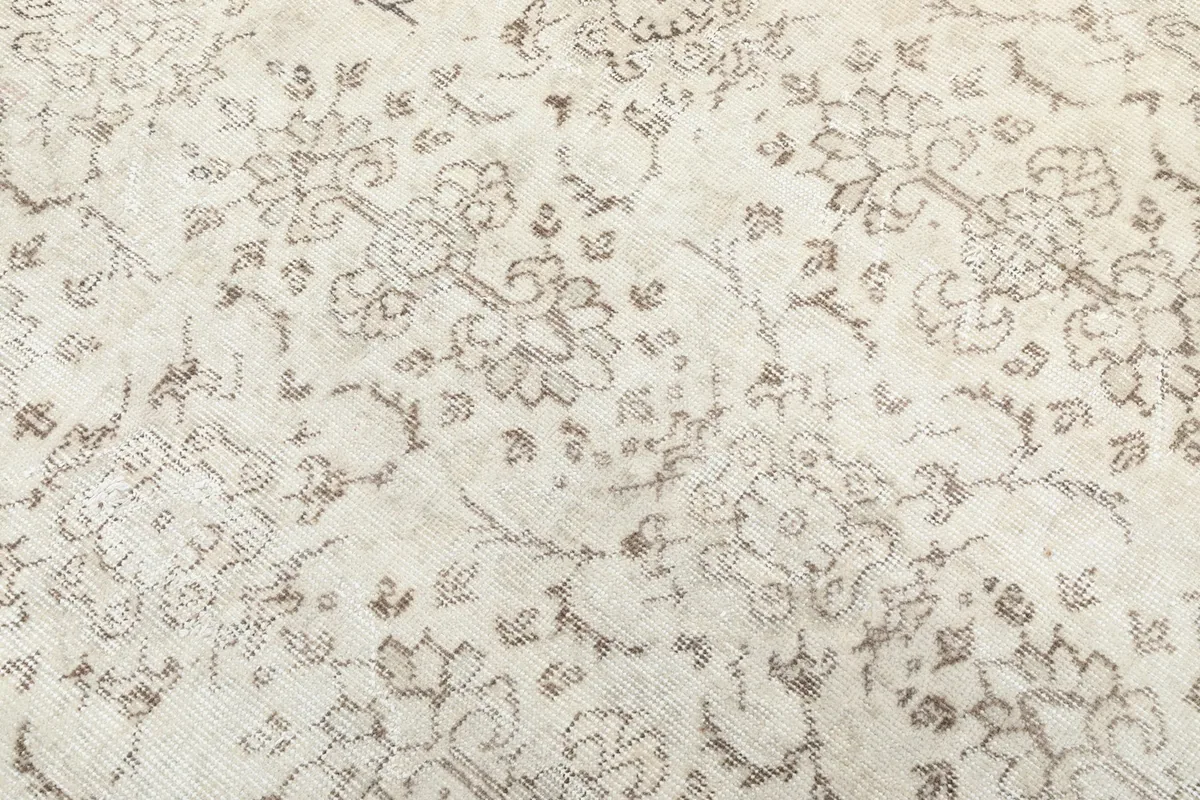Close-up of the hand-knotted wool pile and the intricate beige floral design