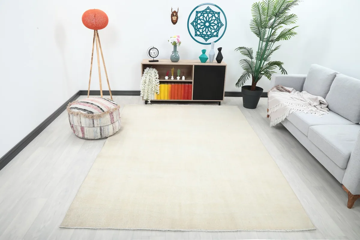 Cream vintage Anatolian rug in a modern living room setting with a gray sofa and light wood furniture.