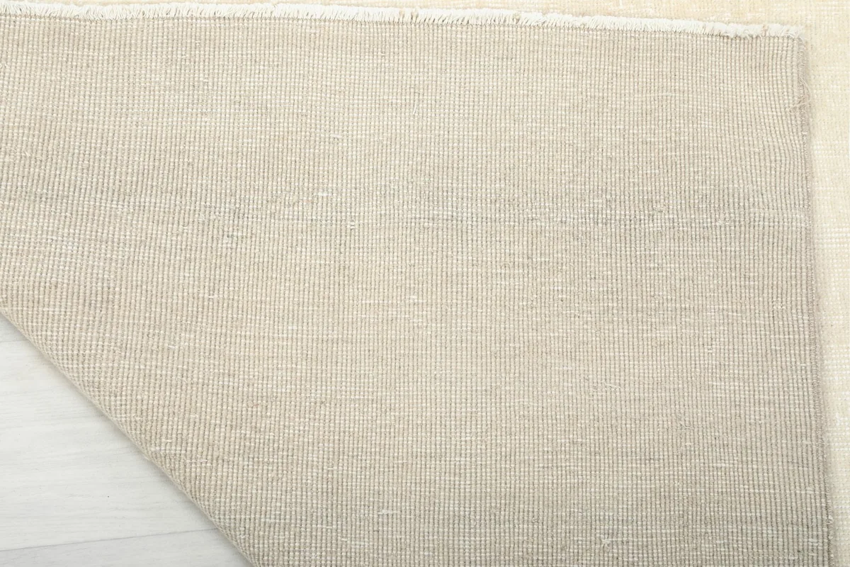 Detailed view of the rug's cotton foundation and tight hand-knotted construction from the back.