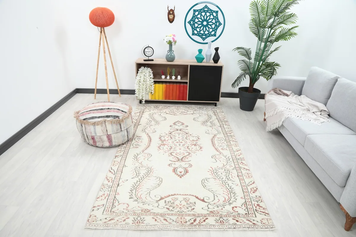 Vintage Anatolian rug in a living room setting, showcasing its ivory, rust, and gray tones.