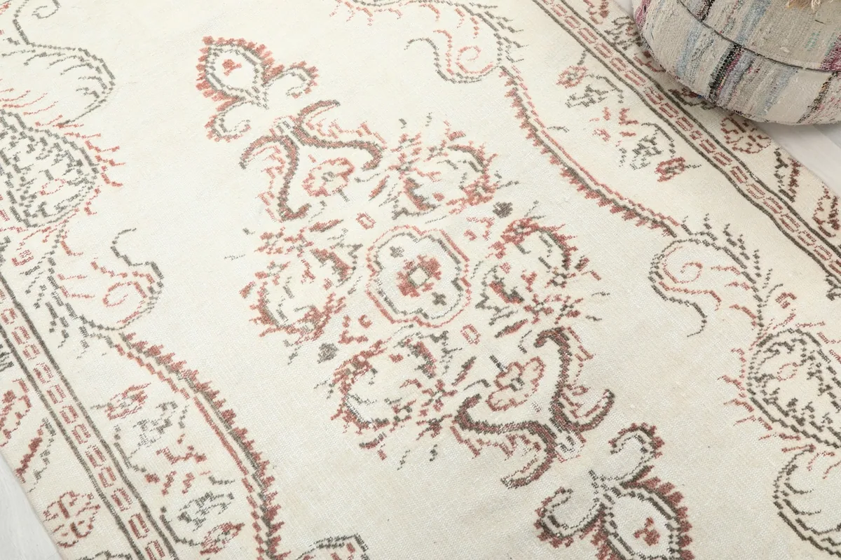 Close-up detail of the central floral and geometric motifs in rust and gray on an ivory field.