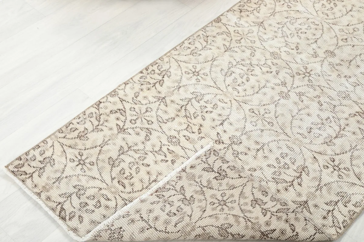 Corner of the rug folded back, revealing the wool pile and cotton foundation.