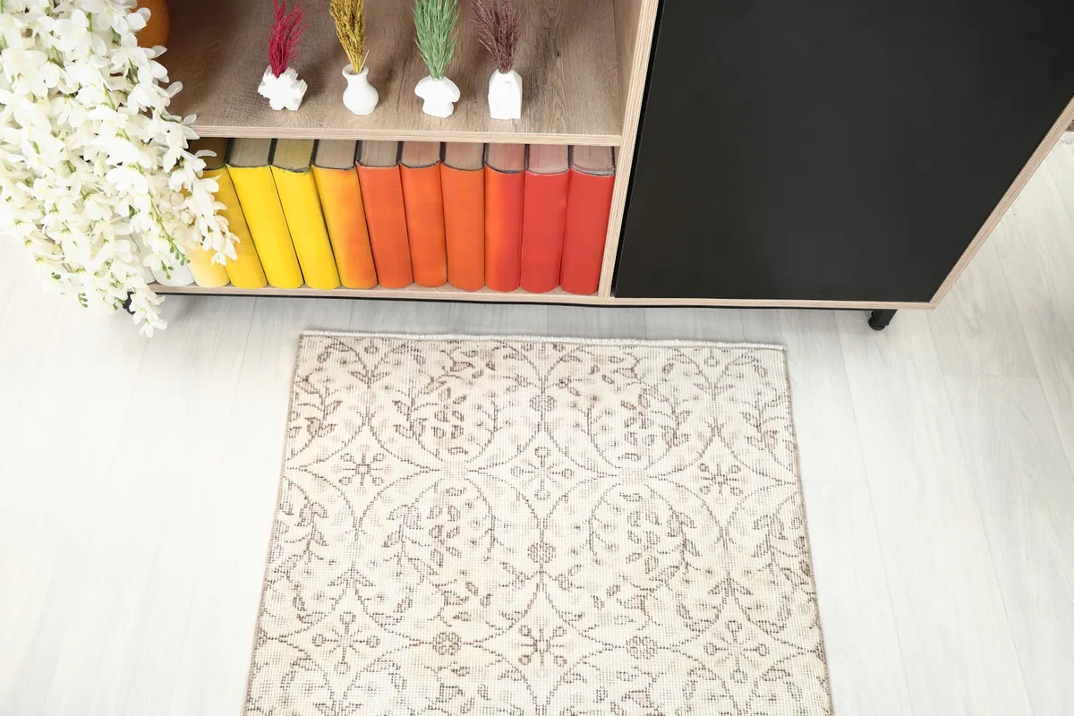 Top-down view of one end of the cream and tan runner rug next to a bookshelf.