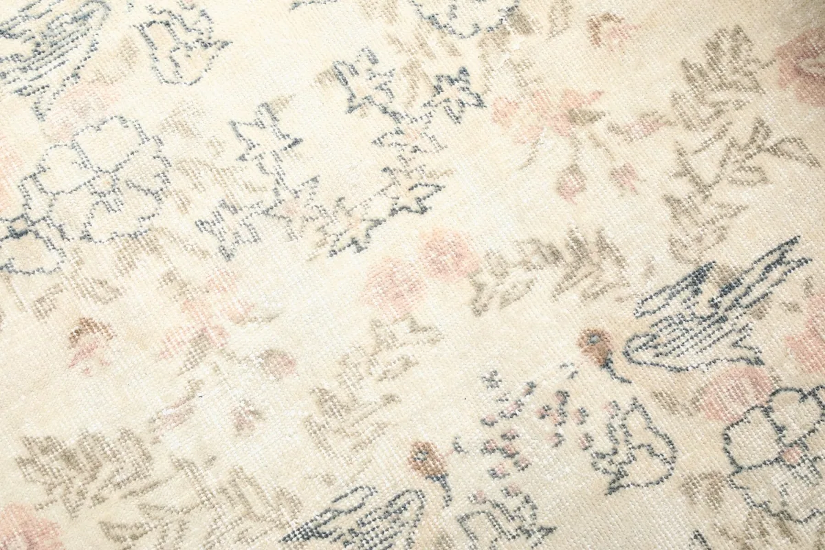 Close-up of the wool pile and intricate floral and bird patterns in various colors