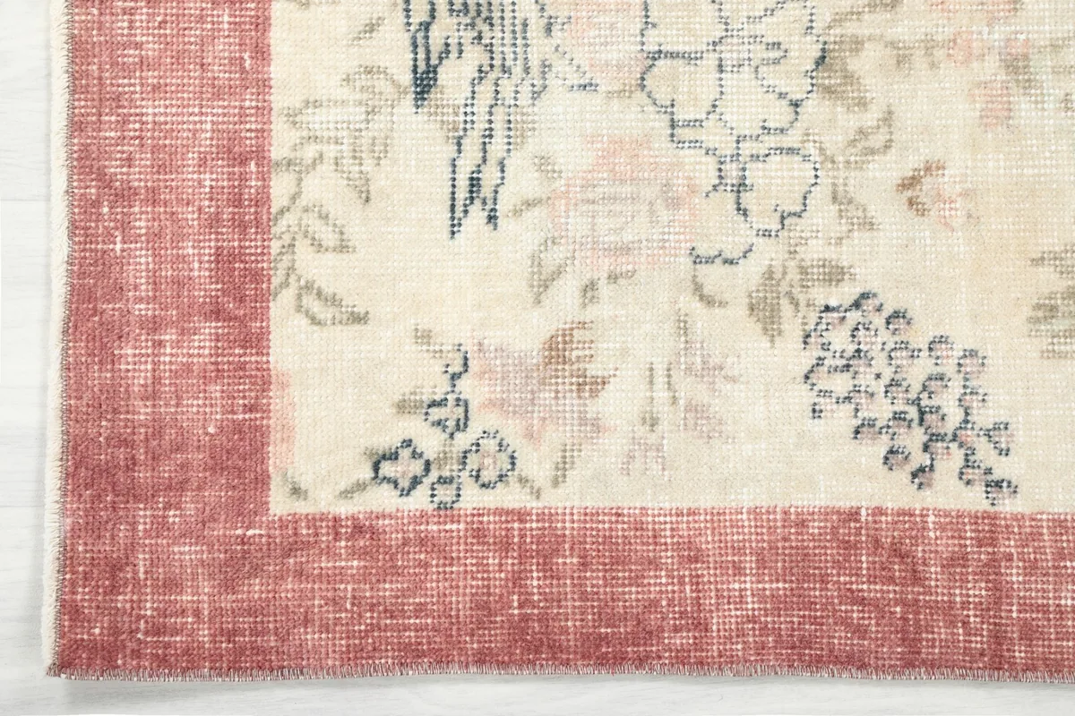 Corner detail of the rug, showing the distressed rose border and part of the ivory field design