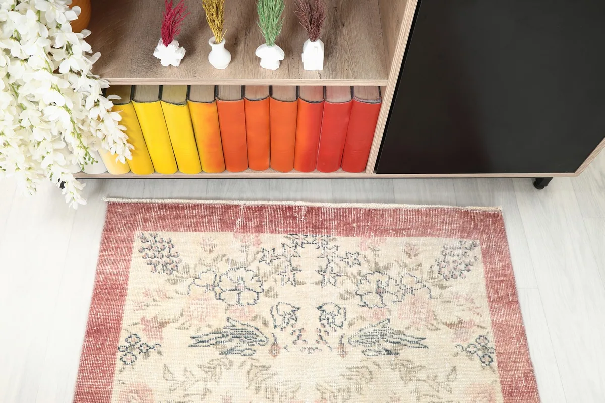 Overhead view focusing on the upper section of the rug, detailing the ivory field and rose border