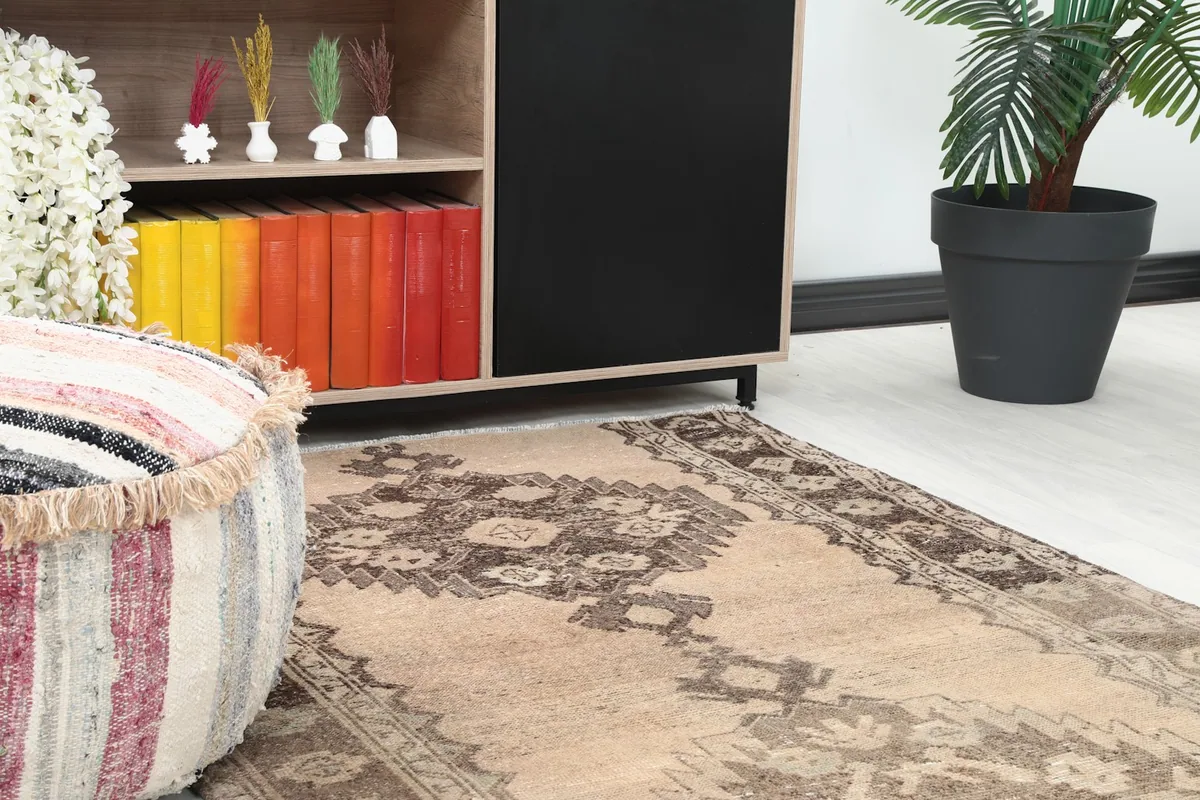 Close-up of the rug's pattern and colors near a decorative ottoman and cabinet.