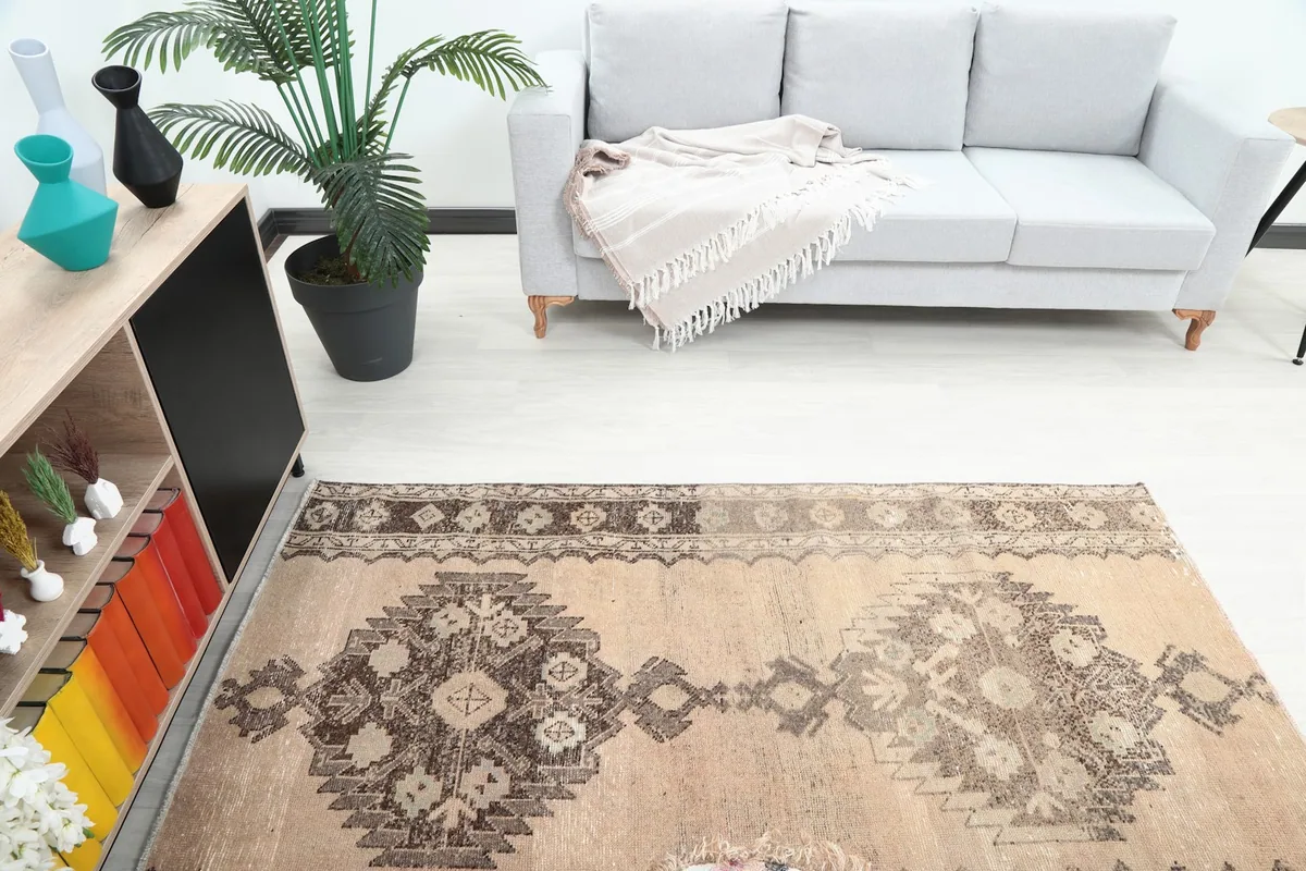 Overhead view showing the tan and brown rug in a room with a light gray sofa.