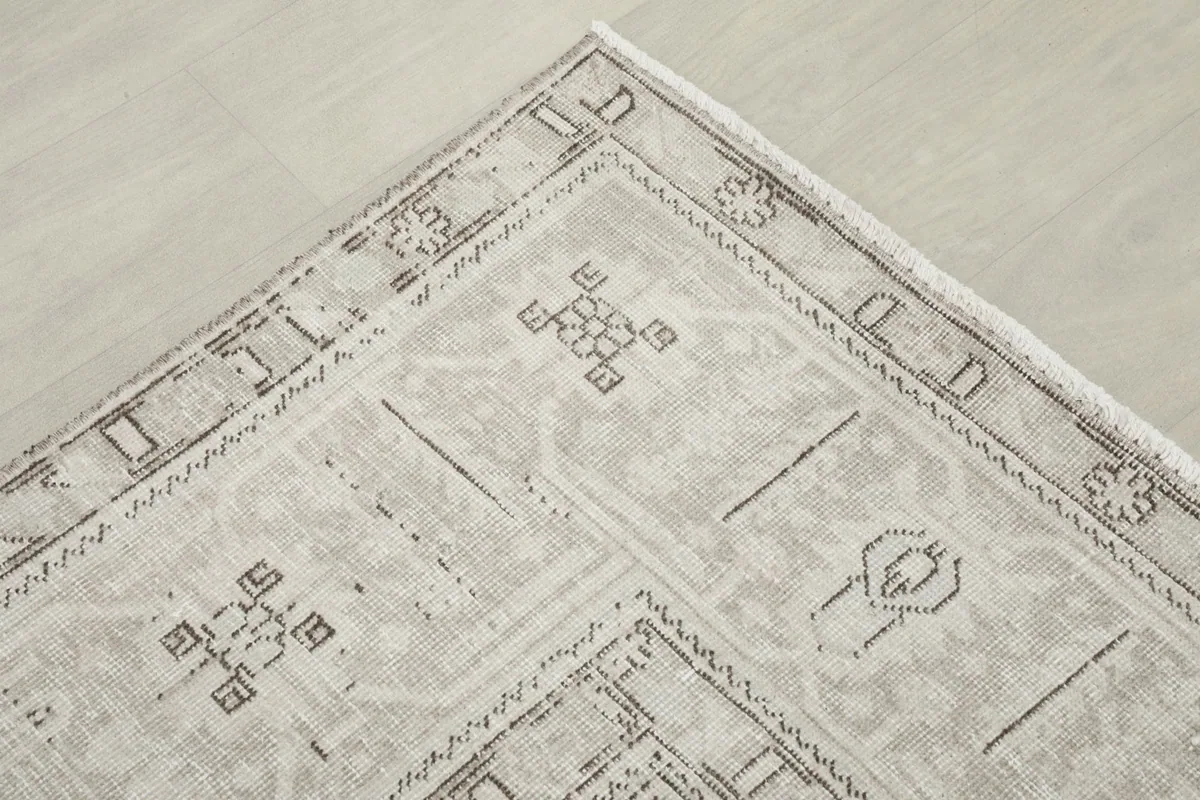 Corner detail showing the geometric border design and faded texture of the rug.