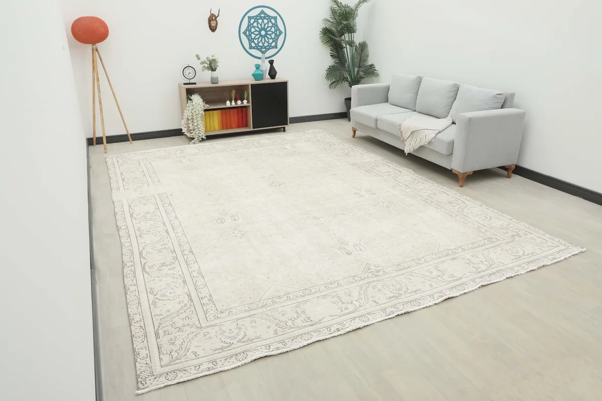 Oversized ivory rug laid out in a modern living space with a gray sofa and minimalist decor.