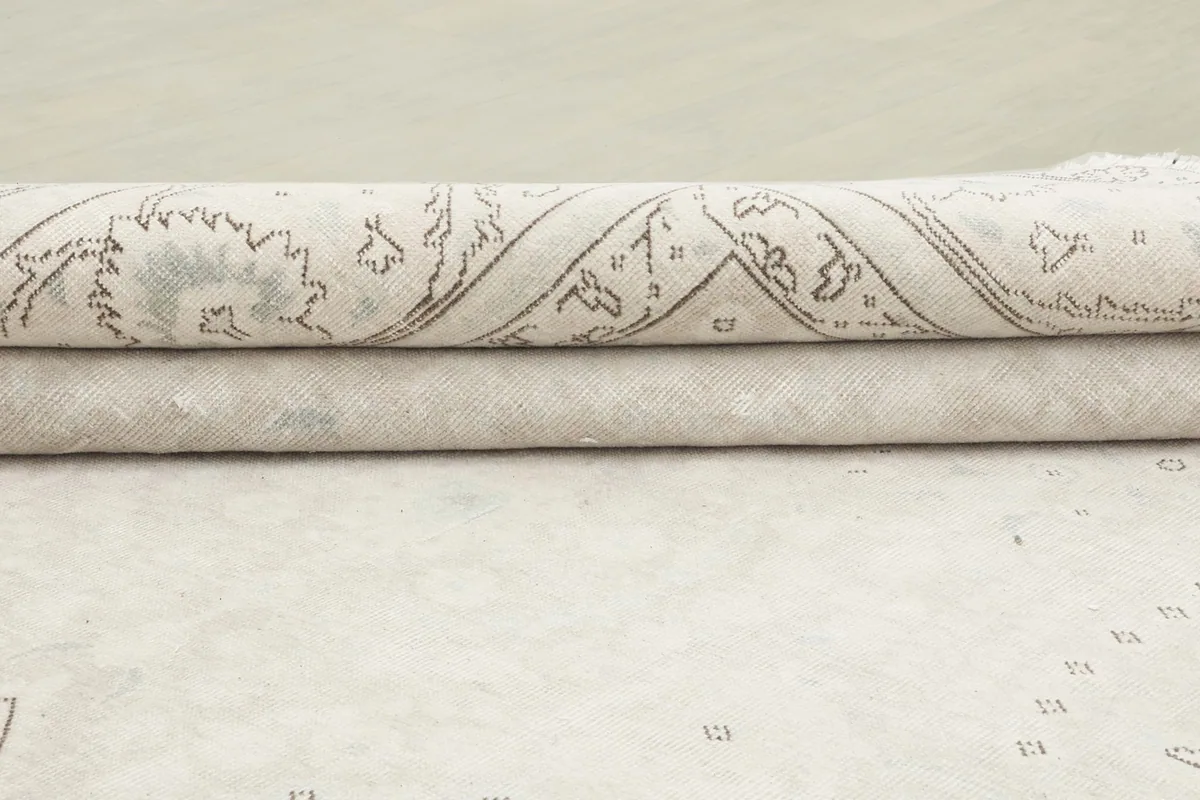 Side view of the rug's rolled edge, illustrating the low pile height and wool material.