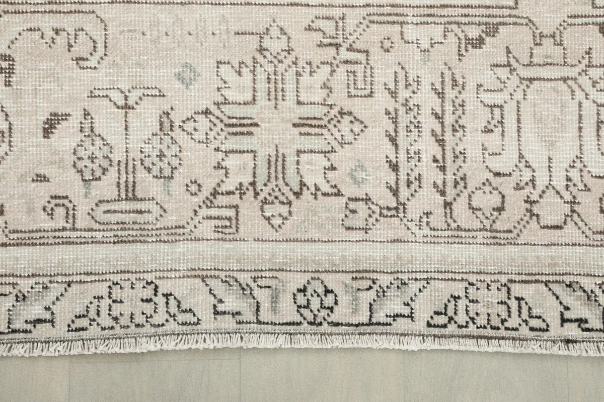 Close-up of the rug's border design and fringe, showing the hand-knotted craftsmanship.