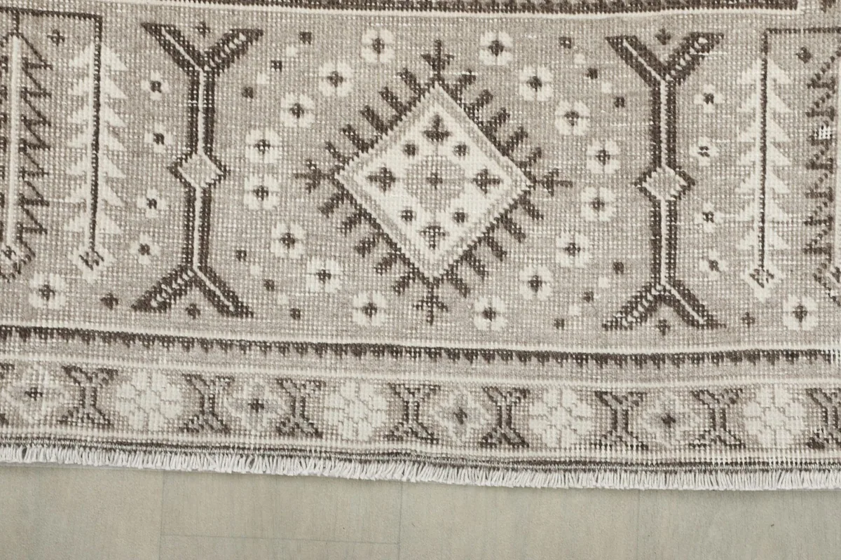 Edge view of the rug, showing the border pattern, fringe, and a diamond motif