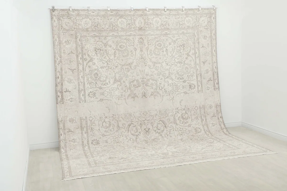 Angled view of the large cream rug hanging vertically, showing its full design and scale