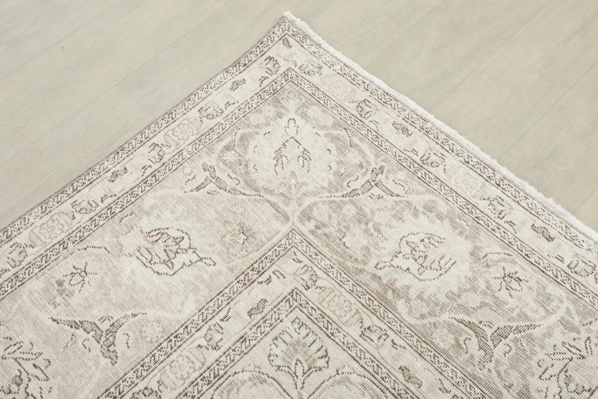 Corner view of the rug, showing the detailed border design with cream, gray, and tan tones