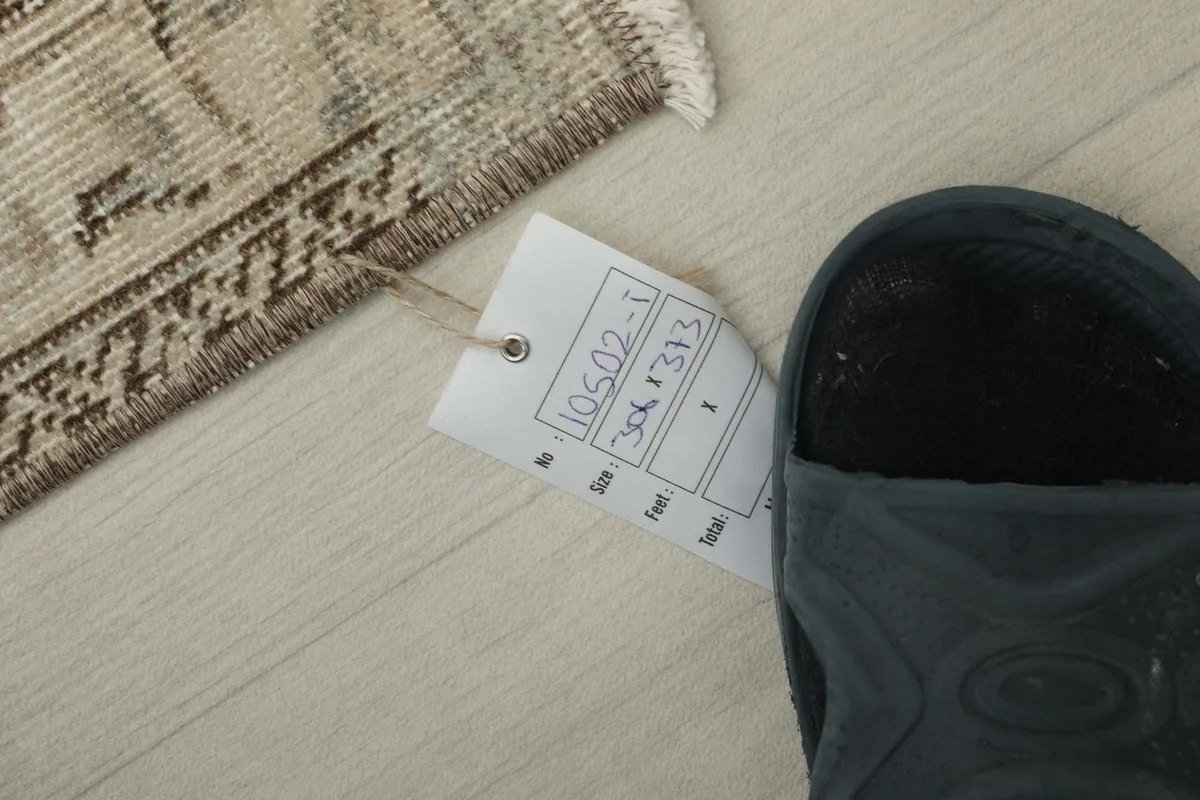 Size tag with dimensions 10'0" x 12'3" (306 x 373 cm) next to a shoe for scale