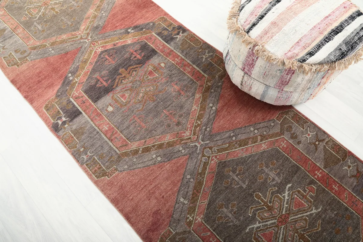 Angled close-up of the rug's geometric medallions and rust field in a room setting.