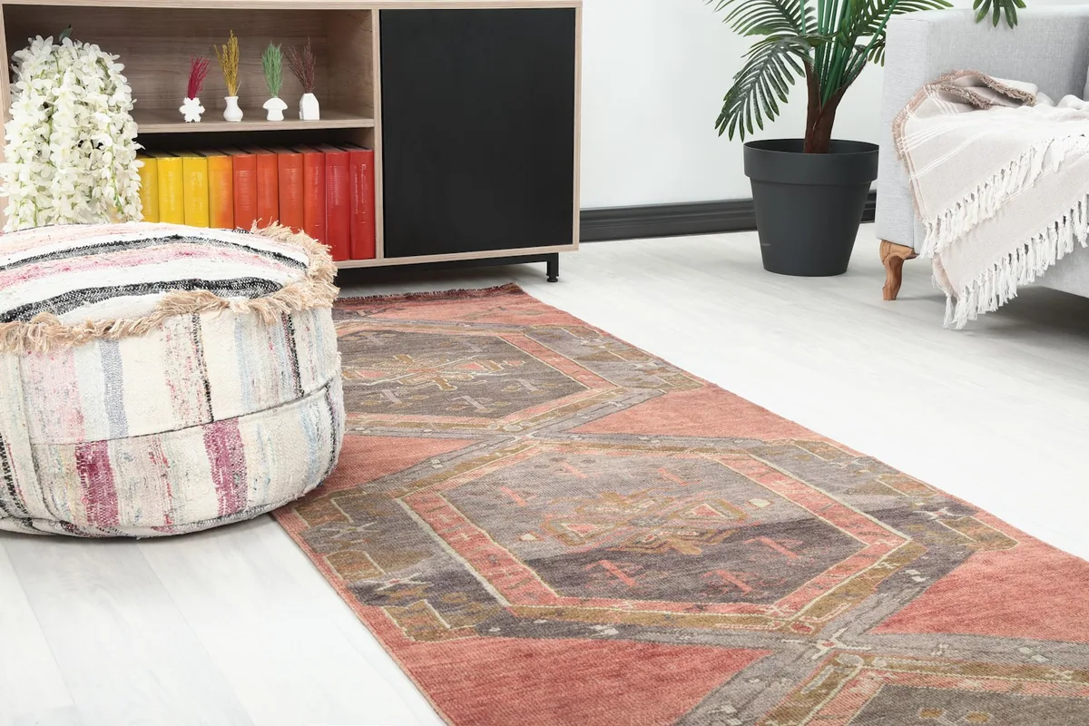 Close-up view of the runner rug in a room, showing the geometric pattern and colors near a pouf.