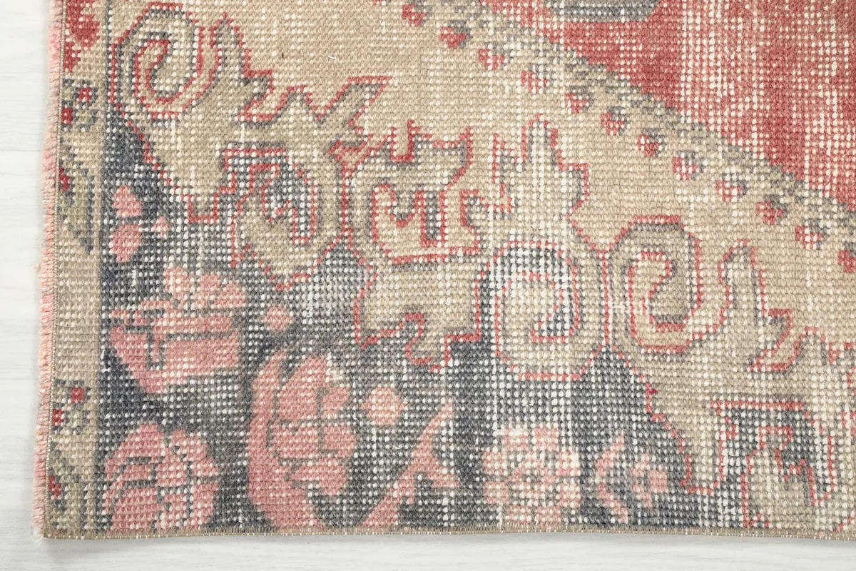Detail of the rug's corner, showing the distressed edge and patterns