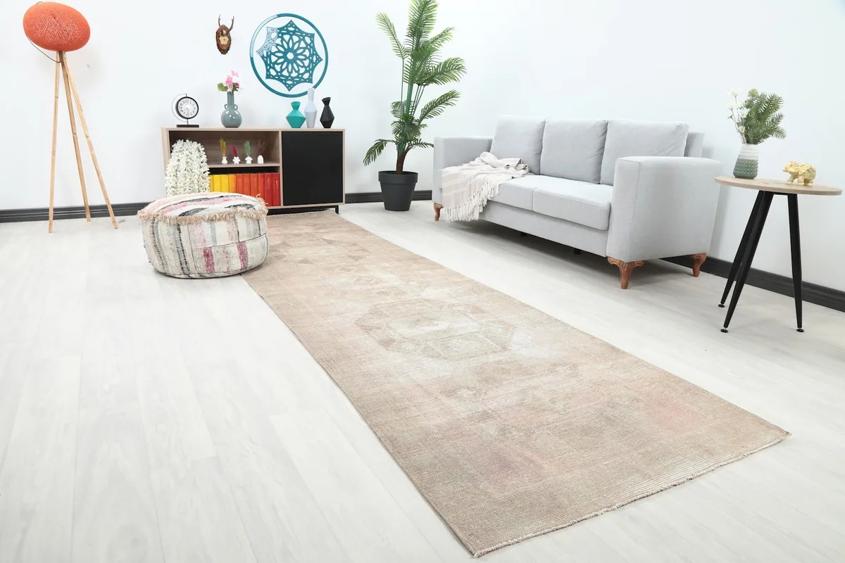 Angle view of the beige and rose runner rug in a room setting, highlighting its long length