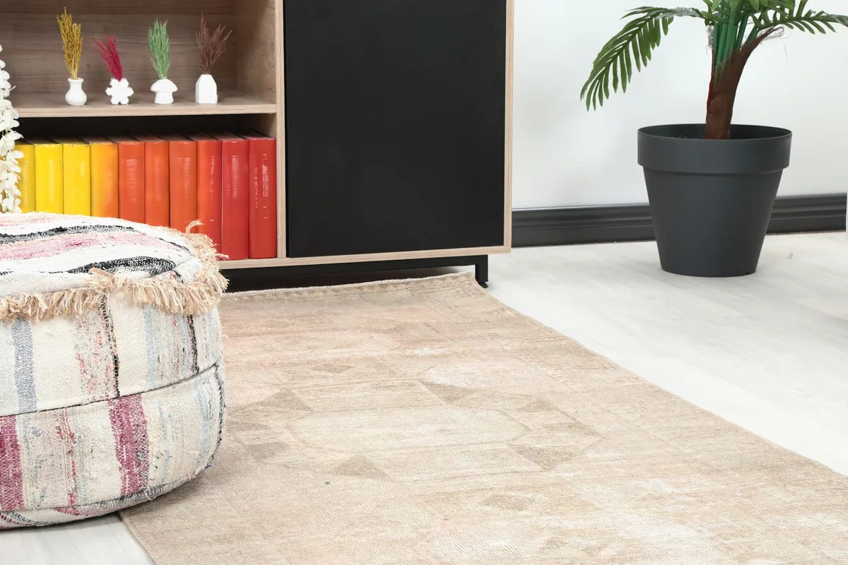 Close-up of the runner rug showing its subtle geometric motif and muted colors next to a pouf