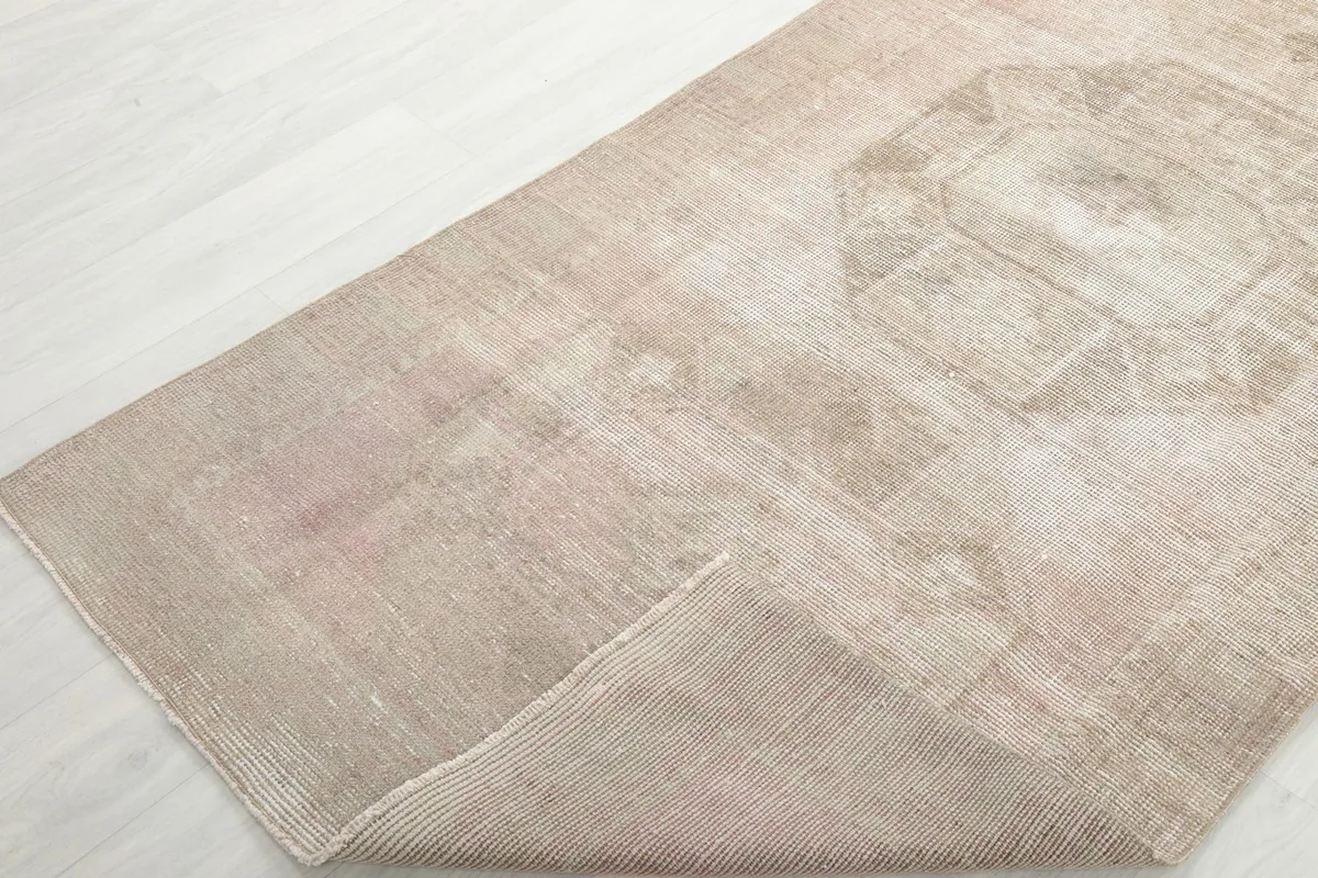 Corner of the runner rug folded back, revealing the reverse side and foundation
