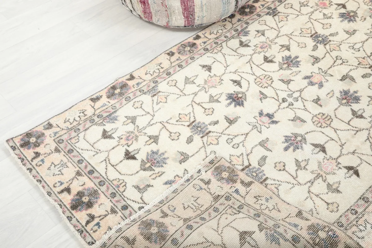 The ivory floral rug partially folded, revealing the soft texture and subtle color variations.