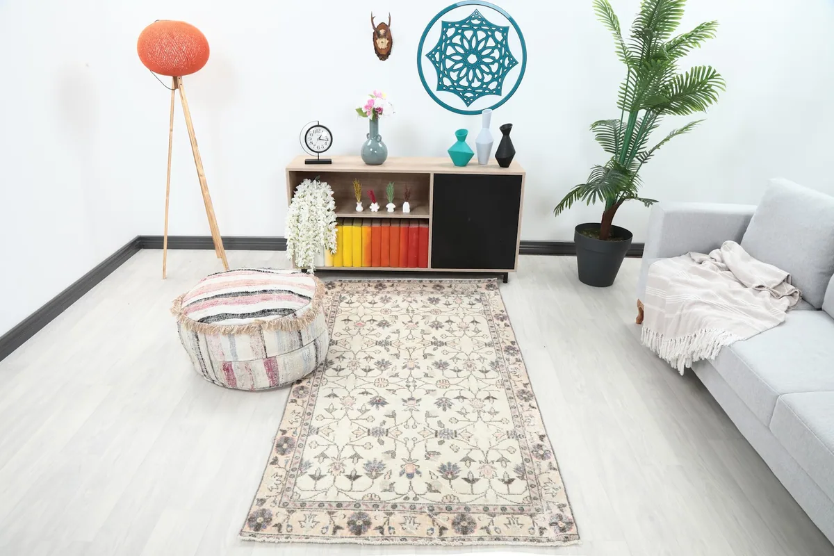Ivory floral vintage rug in a living room setting with a light gray sofa and wooden cabinet.