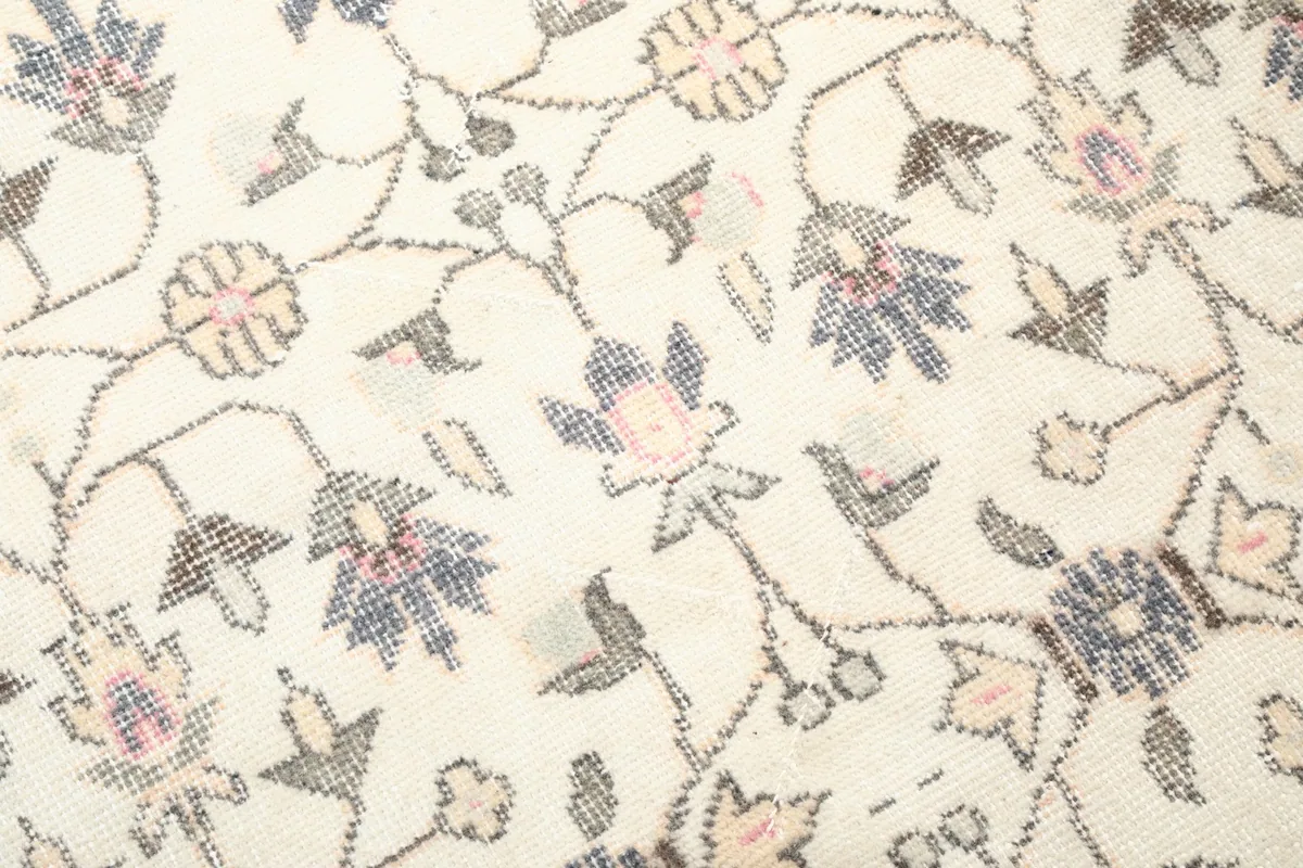 Close-up of the hand-knotted wool pile, showing the texture and faded colors of the floral design.