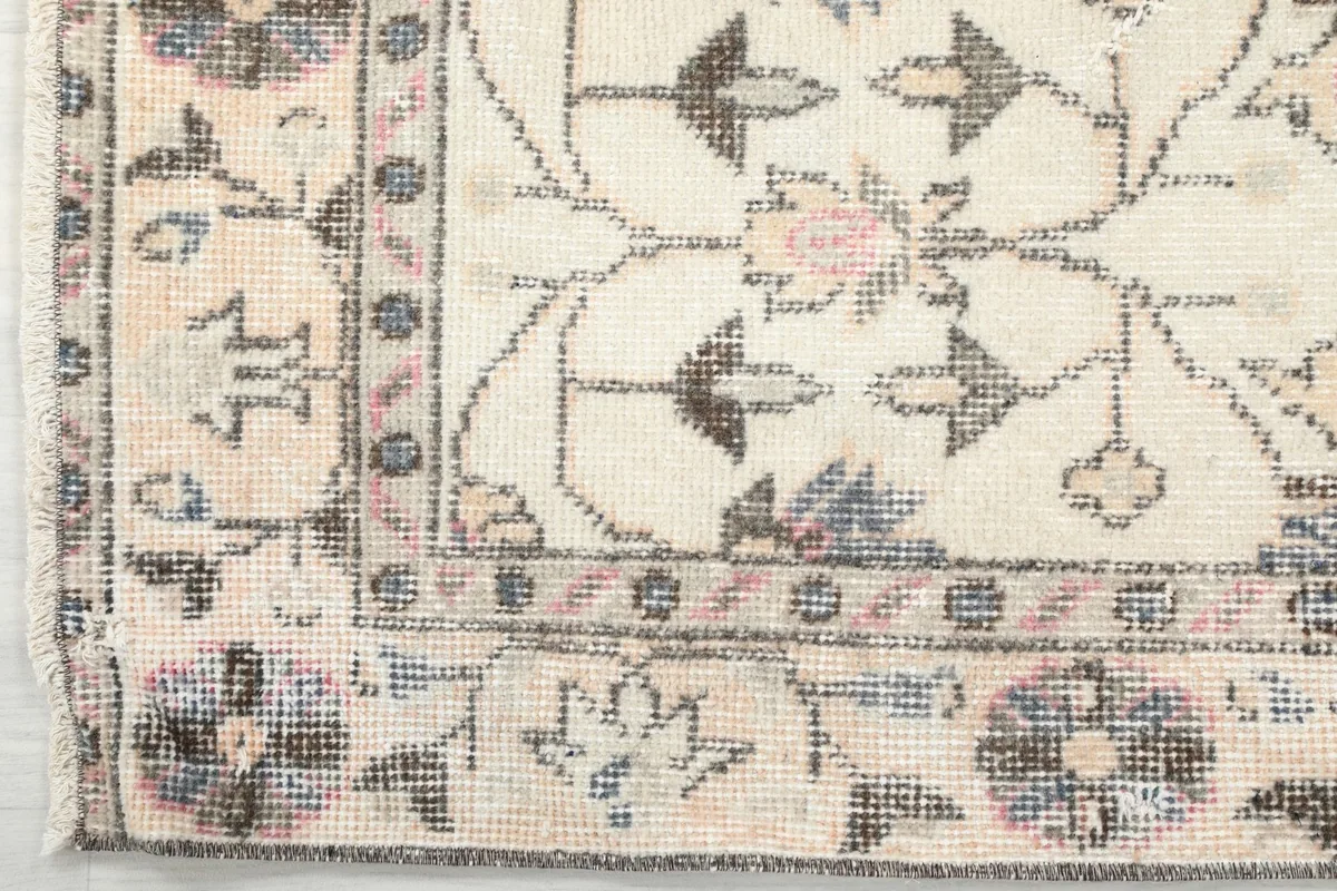 Corner detail of the rug, illustrating the intricate border design and natural wear.