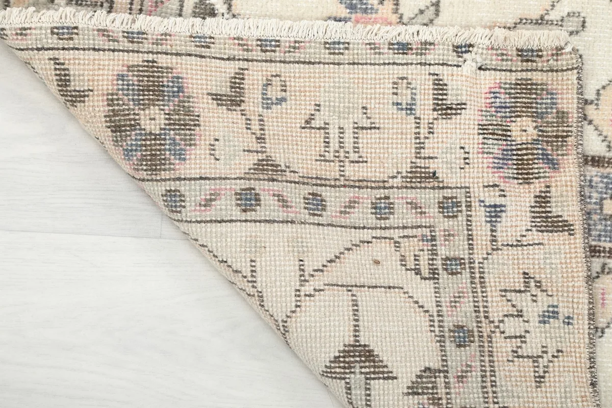 View of the rug's back, showing the cotton foundation and the reverse of the hand-knotted pattern.