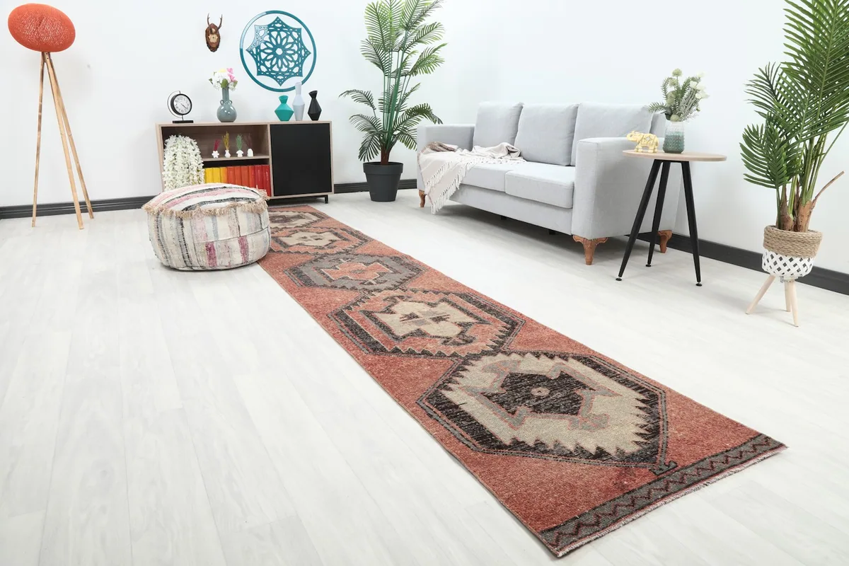 Angled view of the rust geometric runner rug in a room, showing its length next to a sofa and decorative items.