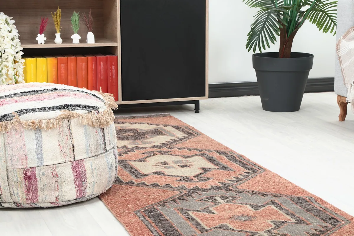 Close-up of a section of the runner rug in a room, showing detail of the geometric pattern near a striped pouf.