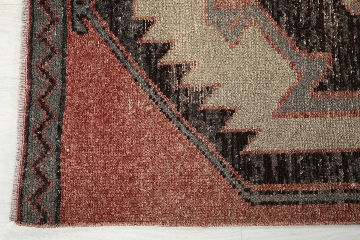 Close-up of the rug's edge, showing the border design and the subtle texture of the vintage wool pile.
