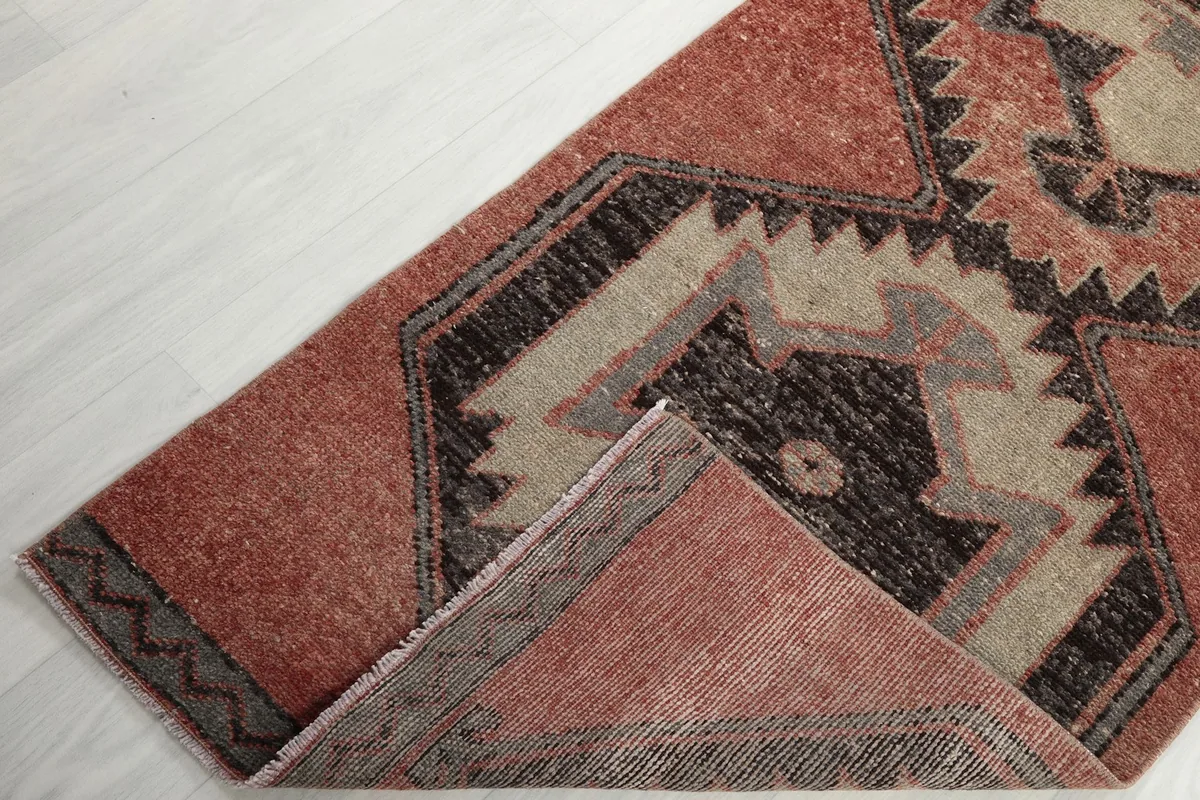 A corner of the rug folded back, revealing the reverse side of the hand-knotted wool on cotton foundation.