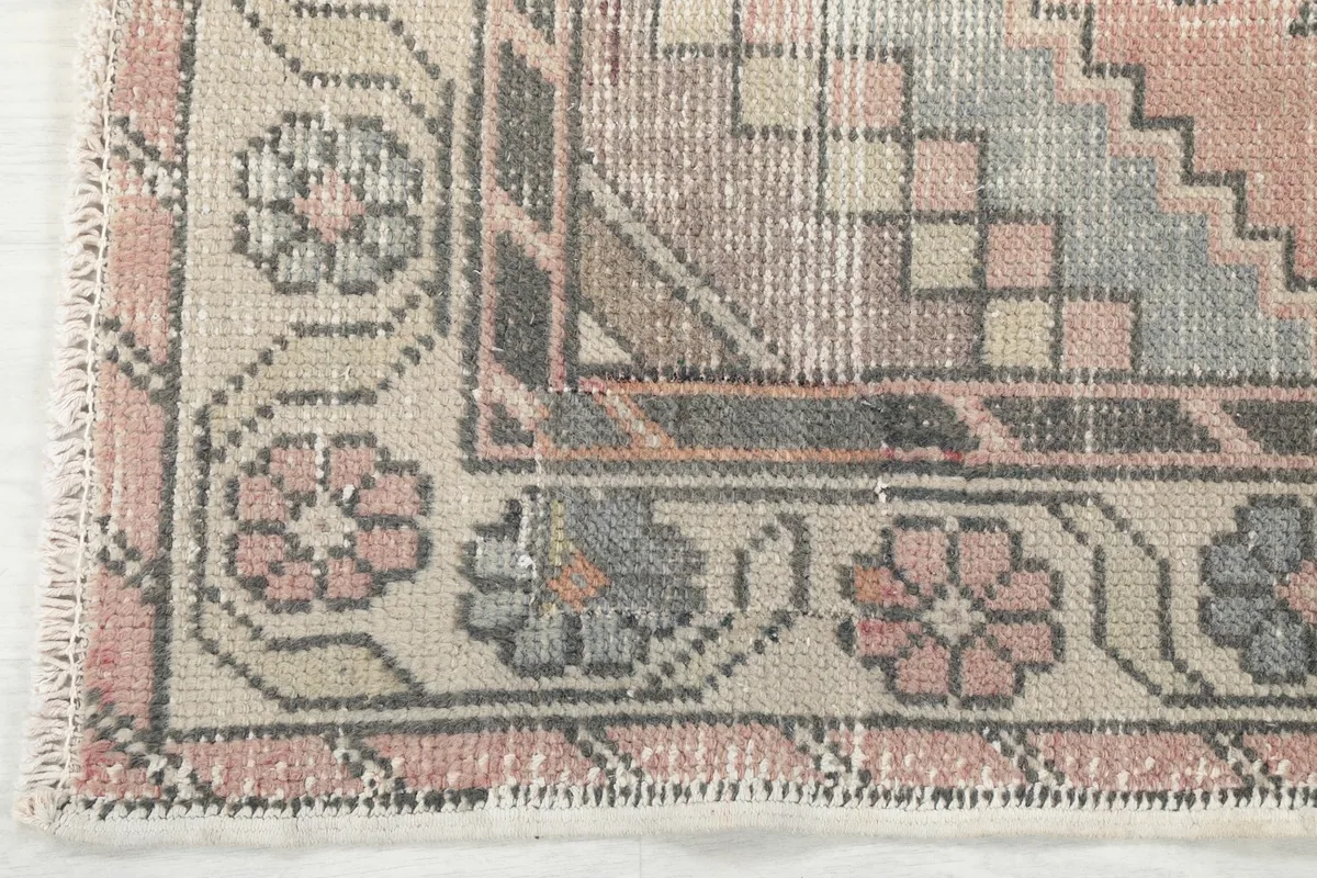 Corner detail of the rug's border pattern, featuring stylized floral elements and fringe