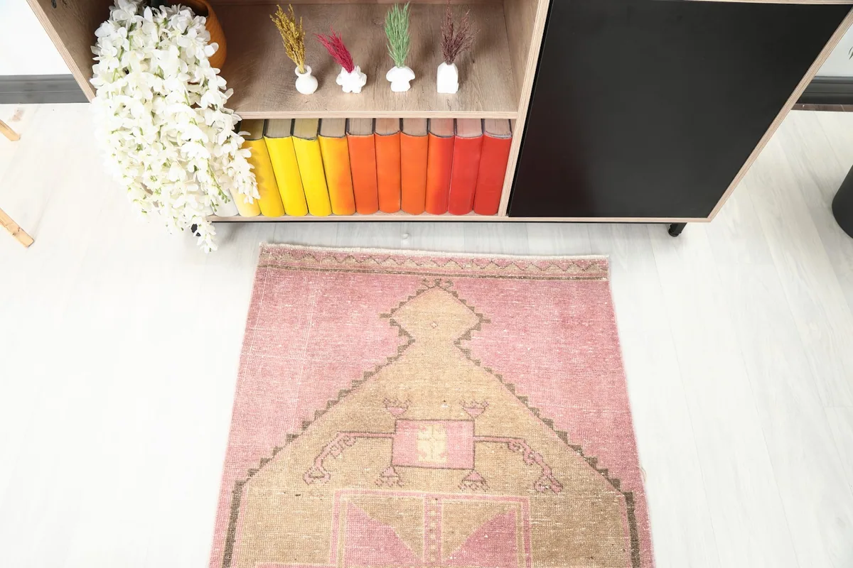Angled view looking down the length of the pink and tan runner rug from one end.