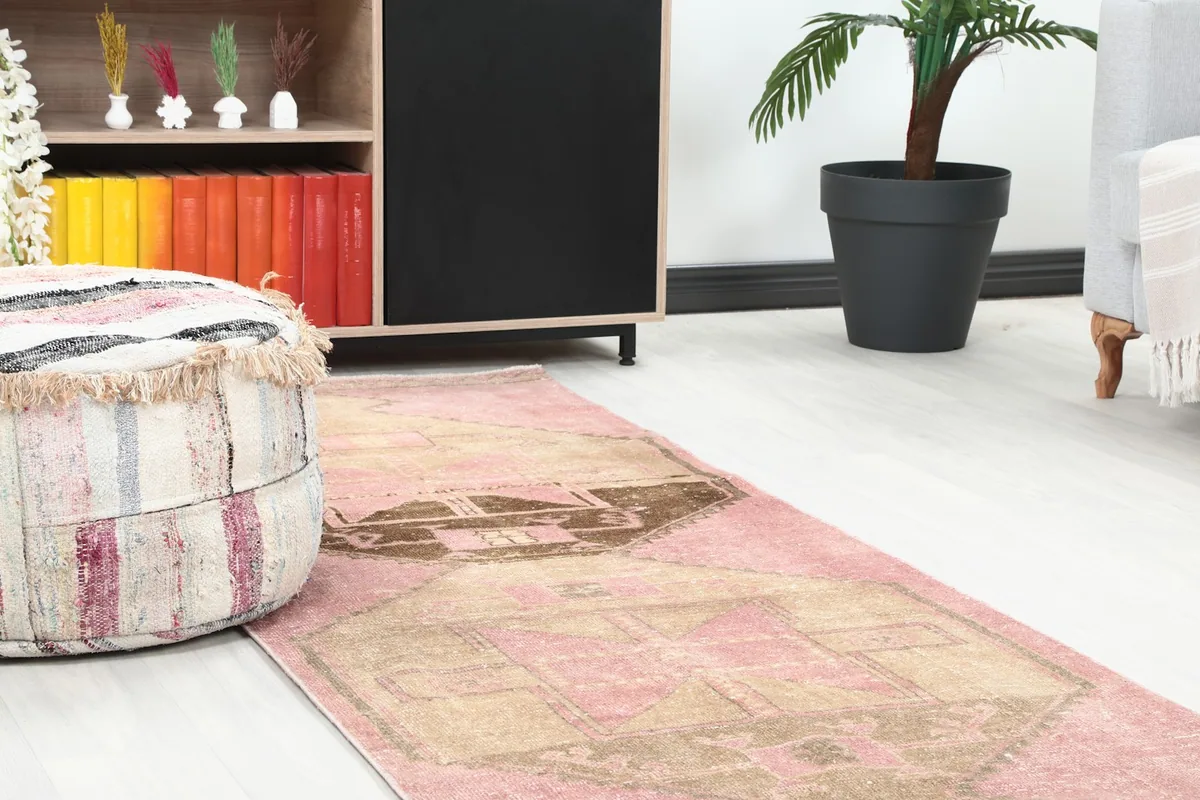 Close-up view of the runner rug's design near a decorative pouf and modern shelving unit.