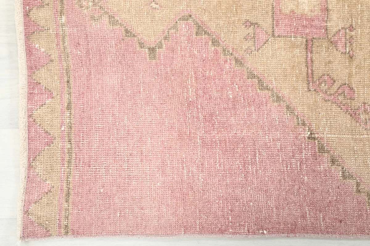 Close-up showing the low pile and texture of the vintage wool runner, highlighting its soft pink hue.