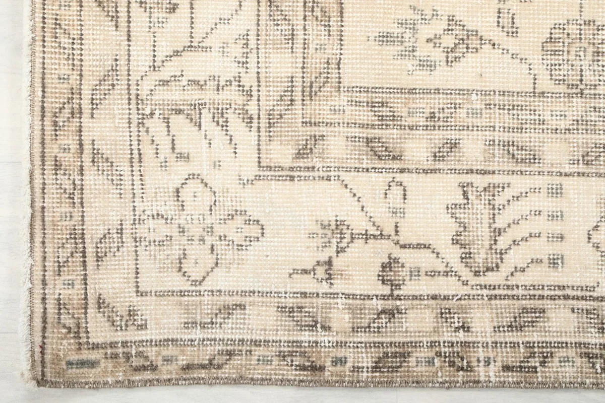 Close-up detail of the rug's tan border with intricate floral motifs and fringe