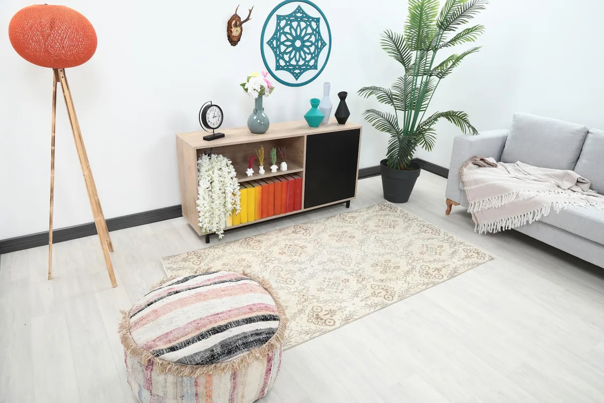 High angle view of the ivory and tan rug in a living room, showing its placement relative to a sofa and ottoman.